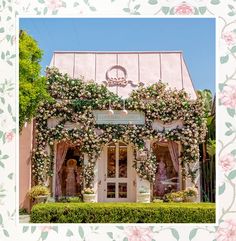 a building covered in flowers and vines with pink roses on the front door, surrounded by greenery