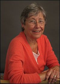 an older woman sitting at a table smiling