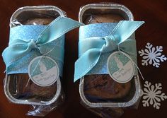 two packages of baked goods wrapped in blue ribbon on a table with snowflakes