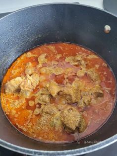 a pot filled with meat and tomato sauce on top of a stovetop burner