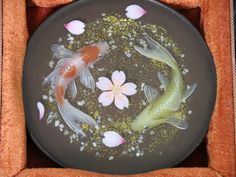 two goldfish in a bowl with water and flowers