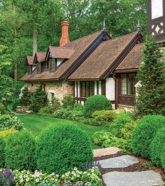 a house surrounded by lush green trees and flowers