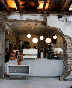 the interior of a restaurant with exposed brick walls and lights hanging from the ceiling over the counter