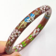 Beautiful Chinese Cloisonné bangle. This stunning bangle has a brick red enamelled base with pink and white Cherry Blossom floral details. There are subtle blue accents throughout and a brass pull open snap hinge. Traditional Chinese Cloisonne style and lovely piece of unusual jewellery for your collection. This bangle will come with a black velour jewellery pouch. DIMENSIONS -    Diameter - 6.4cm (inner) Thickness - 10mm -------------- CONDITION - We work hard to ensure that all of our items ar Red Enamel Bangle Bracelet, Red Enamel Bangle Bracelets, White Cherry Blossom, Enamel Bangle, Unusual Jewelry, Candle Shapes, Flower Bracelet, Sparkling Crystal, Diamond Crystal