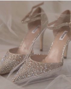 a pair of high heeled shoes on top of a white cloth covered bed sheet