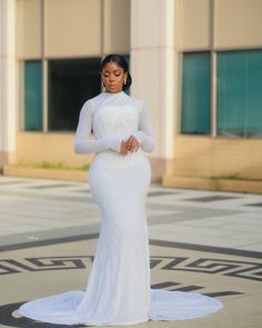 a woman in a white dress is standing on the ground with her hands clasped to her chest