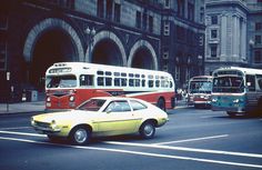 cars and buses are driving down the street in front of large buildings with arched doorways