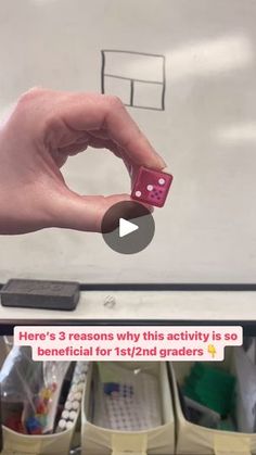 a person holding a dice in front of a whiteboard