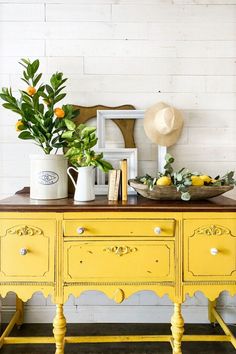 an old dresser painted yellow and decorated with oranges, lemons and greenery