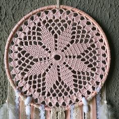 a pink crocheted dream catcher hanging on a wall