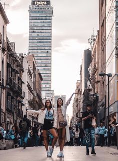 two women are walking down the street with their arms in the air