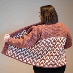 a woman wearing an orange sweater and black pants is holding a large knitted bag