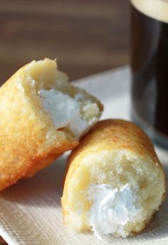 two small pastries sitting on top of a white plate next to a cup of coffee