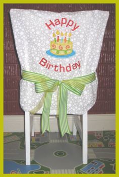 a chair with a birthday cake on it and a green ribbon around the seat cover