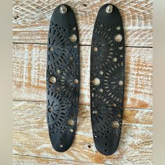 pair of black leather shoes with holes and rivets on wooden background, top view