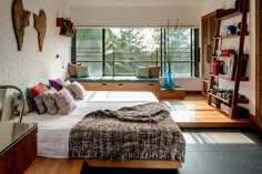 a bed sitting in a bedroom next to a window filled with lots of pillows and blankets