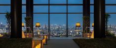 the inside of a building with large windows overlooking city lights and skyscrapers at night