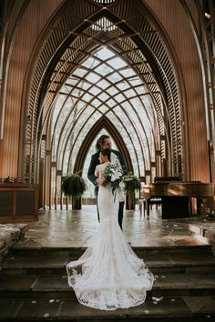 a bride and groom are standing on the stairs in front of an ornate building with stained glass windows