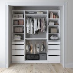 an open closet with white drawers and clothes hanging on the shelves, along with other items