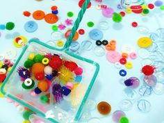 a plastic bag filled with lots of different colored buttons and beads on top of a table