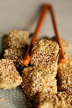 sesame seed balls are stacked on top of each other with orange sticks sticking out of them