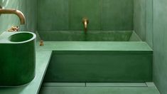 a green bathroom with gold faucet and sink