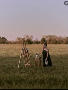 a woman standing next to an easel in a field