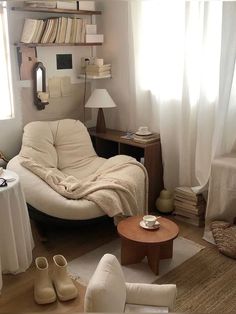 a living room filled with furniture and bookshelves next to a window covered in white curtains