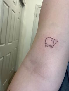 a small black sheep tattoo on the left inner arm and wrist, it appears to be an outline