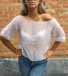 a woman standing in front of a brick wall with her hands on her hips and looking at the camera