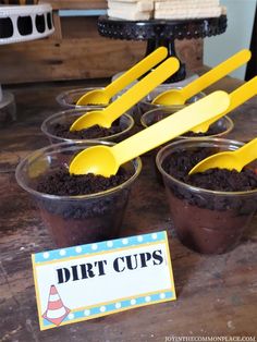 dirt cups with spoons in them and a sign for dirt cups on the table