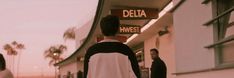 two people walking down the street in front of a delia sign and palm trees