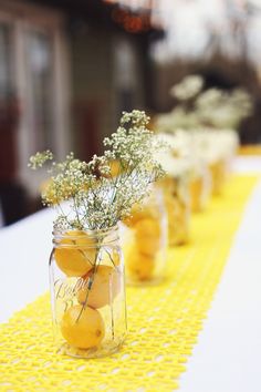 several jars filled with lemons and baby's breath on a yellow table cloth