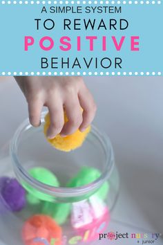 a child's hand reaching into a glass bowl filled with play dough and colorful letters