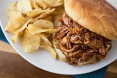 a pulled pork sandwich and potato chips on a plate