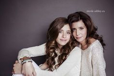 two young women hugging each other in front of a gray background