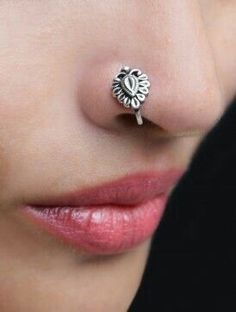 a close up of a person wearing a nose ring with a flower design on it