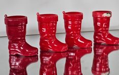 four pairs of red rain boots sitting on top of a table