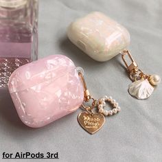 two airpodss sitting on top of a table next to a glass bottle and some beads