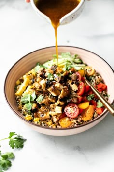 someone is pouring dressing into a bowl of food that includes rice, tomatoes, and other vegetables