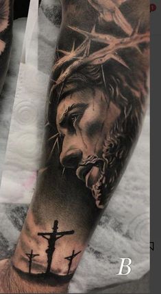 a man's arm with jesus on the cross and crown of thorns tattoo design