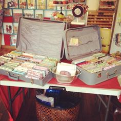 two open suitcases sitting on top of a red table next to a basket filled with books