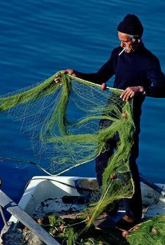 a man standing on a boat holding some green fishing nets