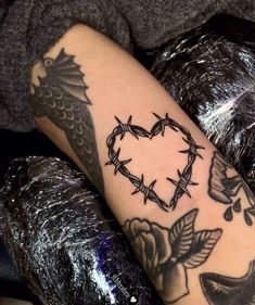 a tattoo on the arm of a person with a heart and barbed wire around it