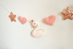 a white swan and pink hearts hanging from a string with star shaped decorations on it