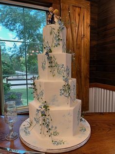 a three tiered wedding cake with figurines on the top and flowers on the bottom