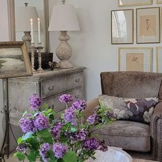 a living room filled with furniture and flowers on top of a coffee table in front of a mirror