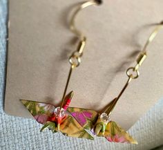 Beautiful hand made origami crane earrings. Made from Yuzen chiyogami paper. Paper is finished with a water based lacquer to help preserve paper and color. Every item is hand made so each item will be unique. Can be made with gold or silver finishings. If you have a preference please let me know. (The silver is sterling silver and the gold is 18k gold plated hooks with a small crystal swarvoski bead added for detail) some are pictured. If you do not want the bead added, please just let me know :)  If there are any issues, will gladly return or resend a new pair made to order. *due to the delicate material, I recommend avoid getting any water or moisture on paper* Crane Earrings, Origami Swan, Chiyogami Paper, Origami Crane, Paper Crane, Christmas Gift Bags, Paper Paper, Cute Packaging, Beautiful Hand