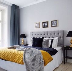 a bedroom with blue and yellow colors on the walls, white bedding, gray headboard