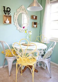 a table with chairs and a mirror on the wall in a room that has blue walls